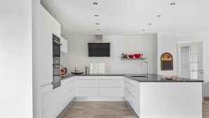A modern kitchen with white cabinetry, a black backsplash, and a wooden floor. - Nice home in Sydals with WiFi (Sydals)