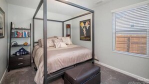 Quarto com uma cama de dossel, mesa de cabeceira, estante e janela com persianas.