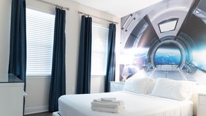 Une chambre d’hôtel moderne dotée d’un grand lit, offrant une vue sur le ciel par une fenêtre, et agrémentée d’une fenêtre circulaire au design original sur le mur.