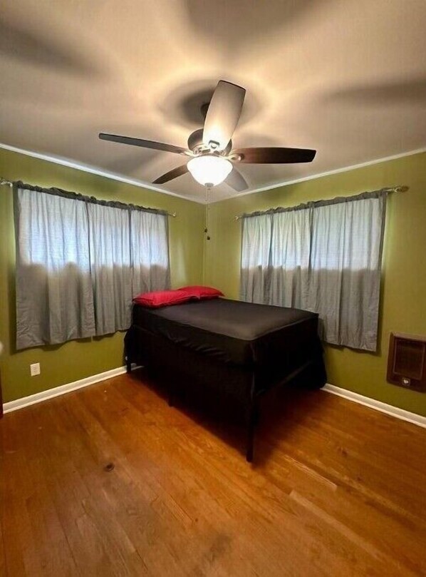 A bedroom with a bed, a ceiling fan, and two windows with curtains. - Spacious Country Home (Tanner)