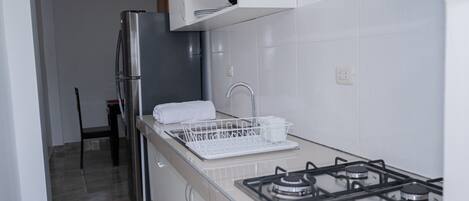 Una cocina moderna con un refrigerador de acero inoxidable, una estufa a gas y un escurreplatos.
