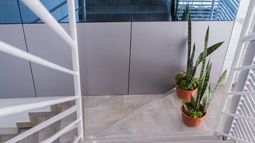 Una escalera con barandillas blancas que conduce a un edificio moderno con amplias ventanas y un muro de azulejos azules.