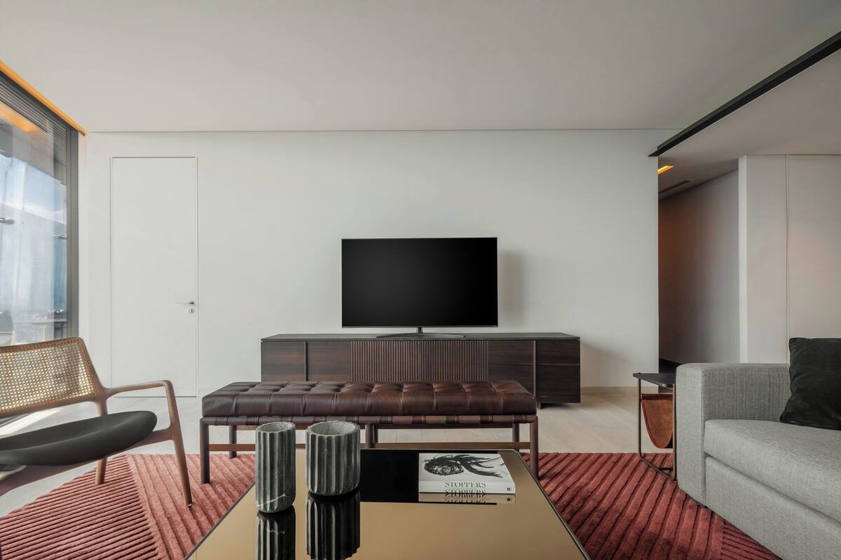 A modern living room with a flat-screen TV, leather sofa, and a coffee table with decorative items.