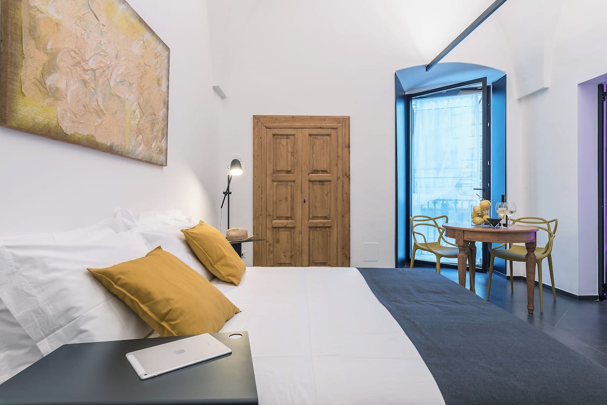 Una habitación de hotel moderna con una cama grande, un escritorio y un área de comedor con sillas.