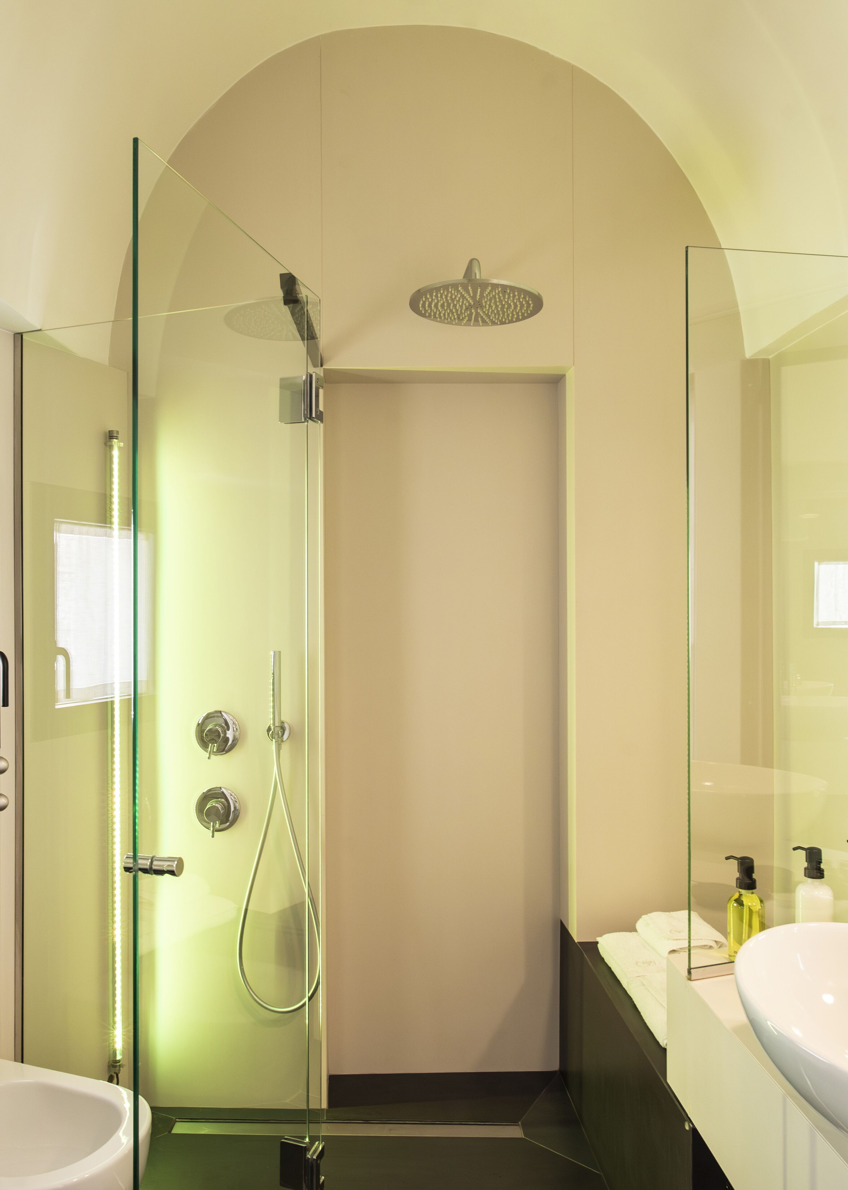 A modern bathroom with a glass-enclosed shower, a white sink, and a mirror.