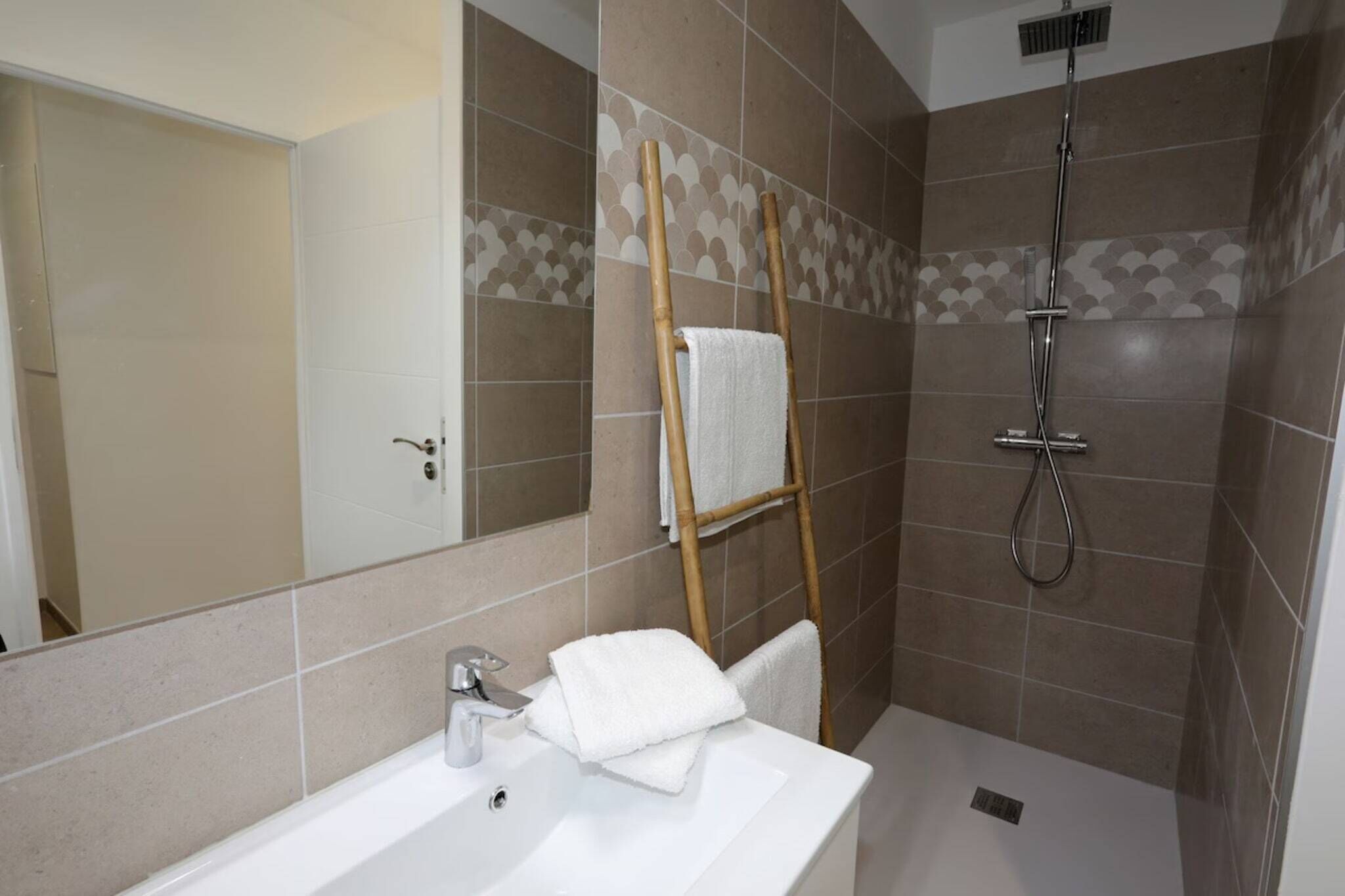 Une salle de bain avec une baignoire, un miroir, un porte-serviettes et une douche.