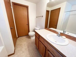 Een badkamer met toilet, wastafel en spiegel.