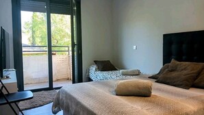 Een slaapkamer met een bed, een televisie en een glazen schuifdeur die leidt naar een buitenruimte.