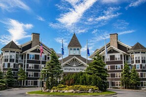 Un hotel con una torre central, varios mástiles de banderas y un cartel que dice 'Allegheny Springs'.