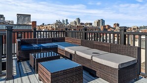 A rooftop terrace with wicker furniture and a city skyline view. - Rare Indoor Heated Pool + Philly Rooftop Deck (Philadelphia)