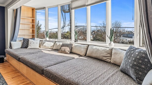 A modern living room with a large window, a built-in bench, and a small table with a plant. - Rare Indoor Heated Pool + Philly Rooftop Deck (Philadelphia)