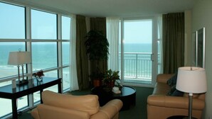 A hotel room with a large window offering a view of the ocean, a sofa, a coffee table, and a lamp. - Three Bedroom, Ocean Front, Luxury Condo, North Myrtle Beach, SC 3945378 (North Myrtle Beach)