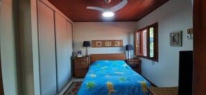 A bedroom with a bed, a dresser, a ceiling fan, and a window with blinds.