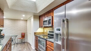 Uma cozinha equipada com geladeira de aço inoxidável, micro-ondas, forno e lava-louças.