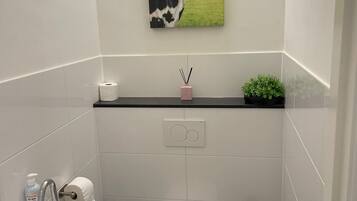 Un baño con inodoro, lavamanos y un cuadro de una vaca en la pared.
