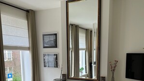 A modern hotel room with a large bed, a fireplace, a TV, and a large window with curtains.