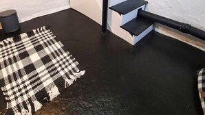A staircase with black railings leading to a lower level, a black and white patterned rug on the floor, and a cylindrical object on the left.