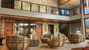 A spacious lobby with wicker chairs, a staircase, and a view of the outdoors. - Príncipe do Muta Hotel Design (Santa Cruz Cabralia)