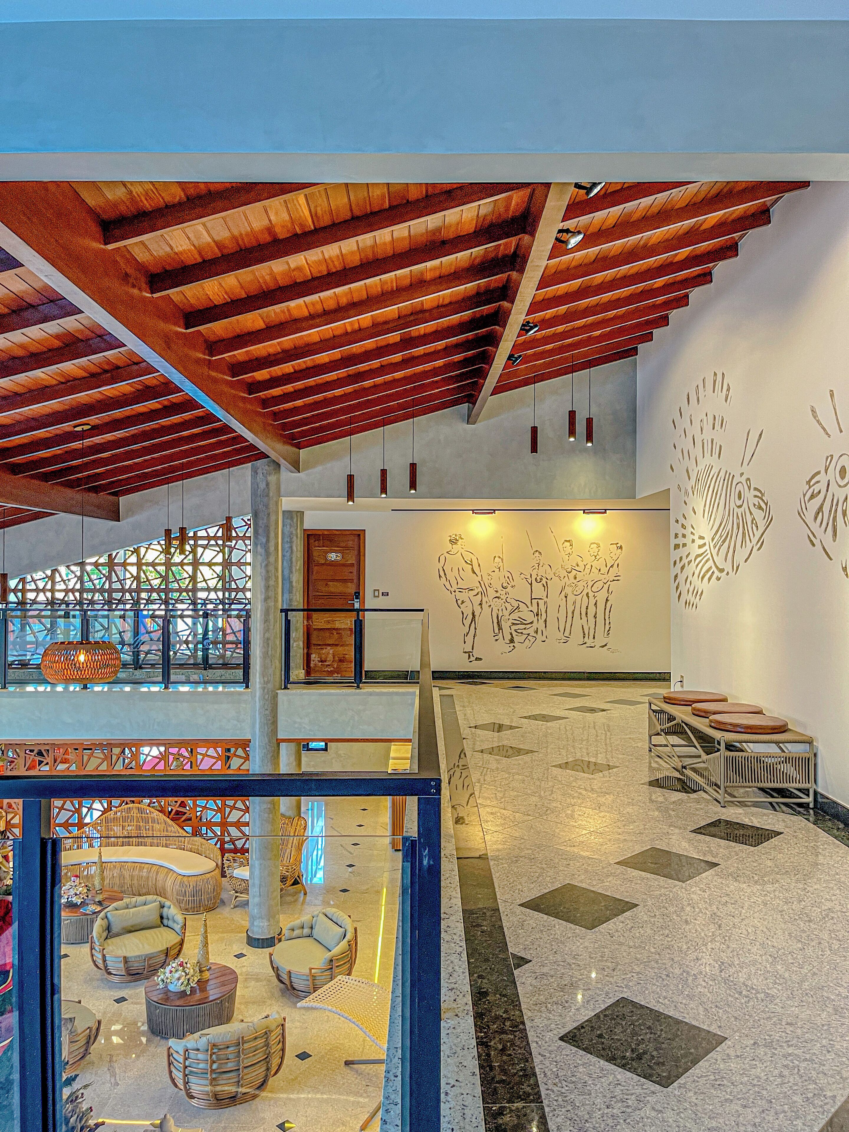 A spacious lobby with a high ceiling, a seating area with round tables, and a wall mural.