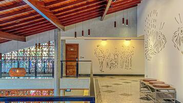 A spacious lobby with a high ceiling, a seating area with round tables, and a wall mural.