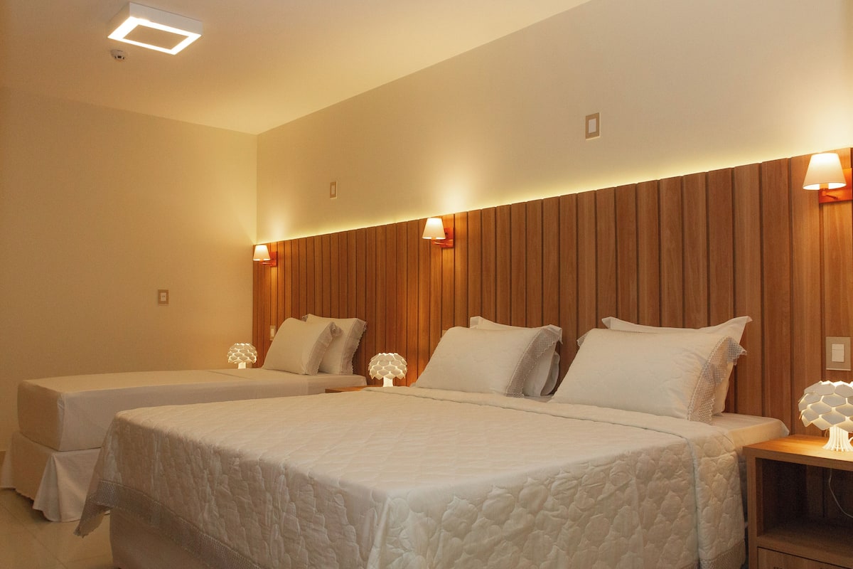Una habitación de hotel con dos camas, paneles de madera en las paredes y lámparas de noche.