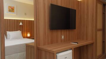 Una habitación de hotel con cama, escritorio con televisor, refrigerador pequeño y lámpara de pared.