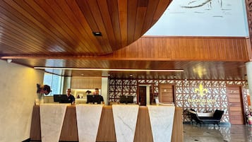 Un espace d’accueil doté d’un plafond en bois, de comptoirs en marbre et d’un mur décoratif orné d’un motif en forme de fleur de lys.