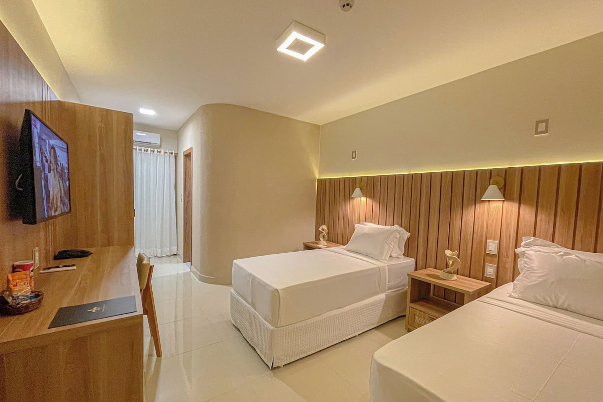 Habitación de hotel con dos camas, un escritorio y televisor.