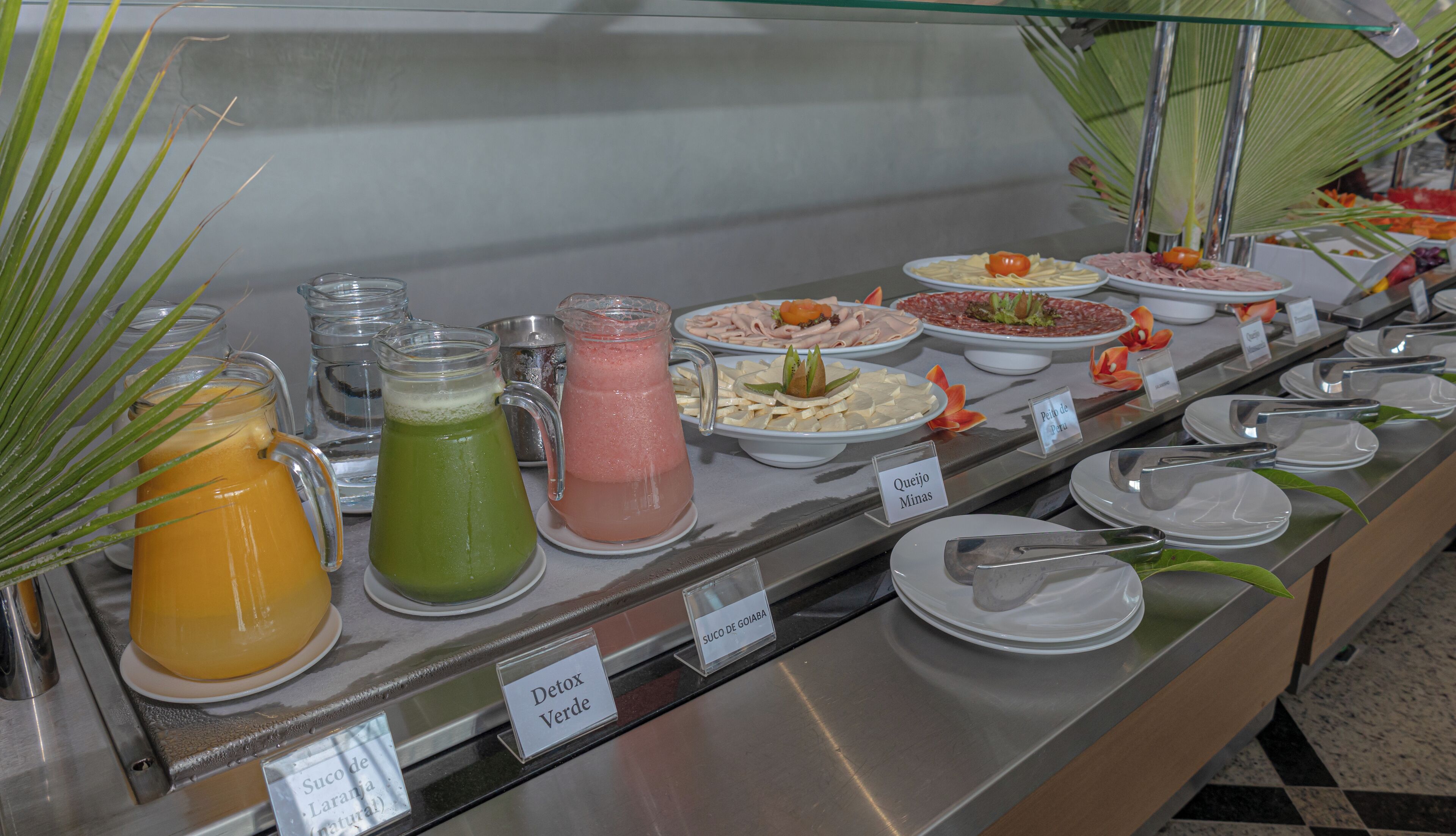 A buffet with various food and drink options, including labeled dishes and a variety of beverages.