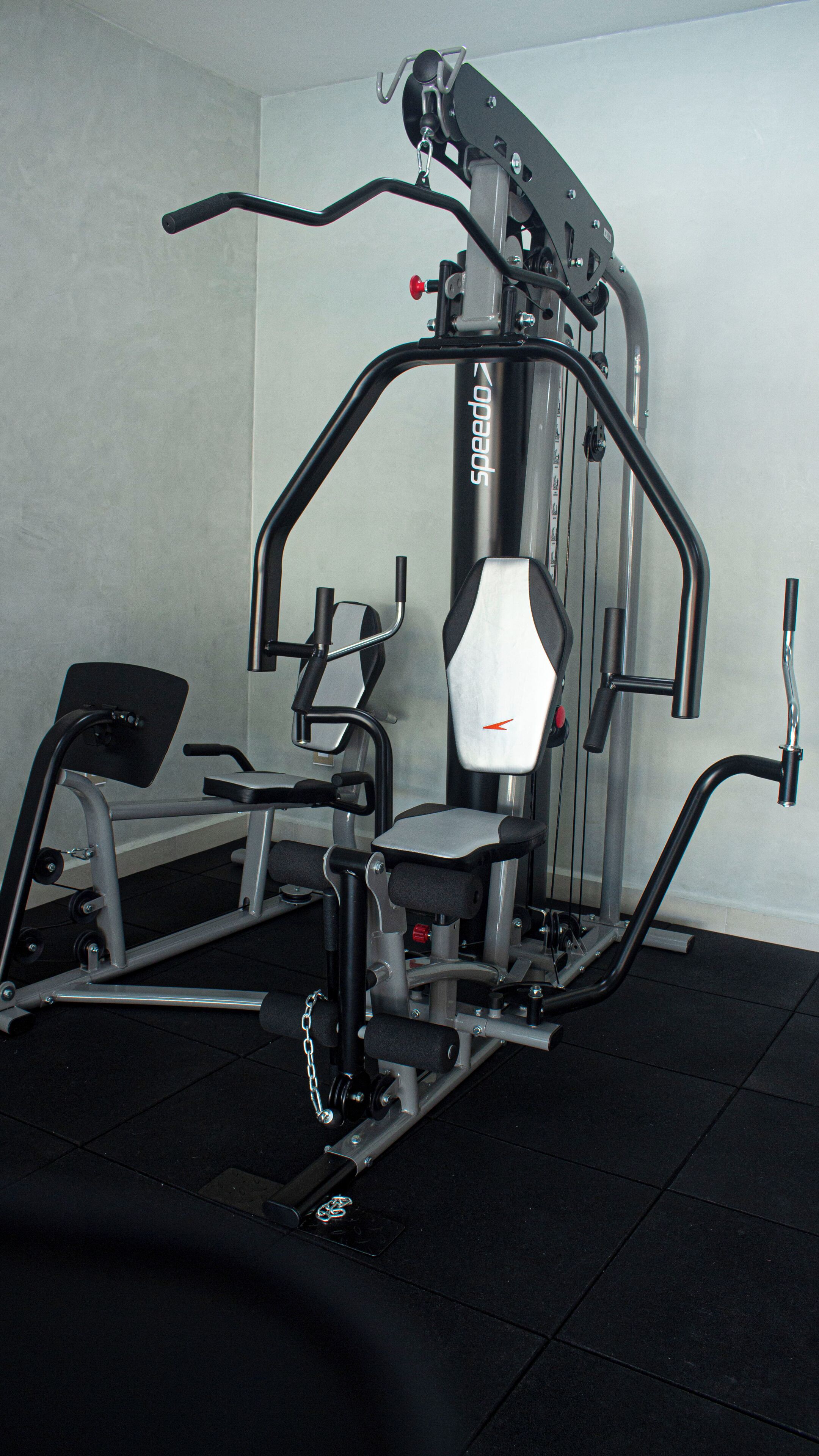 Ein Fitnessraum mit verschiedenen Trainingsgeräten, darunter eine Hantelbank und ein Kabelzug.