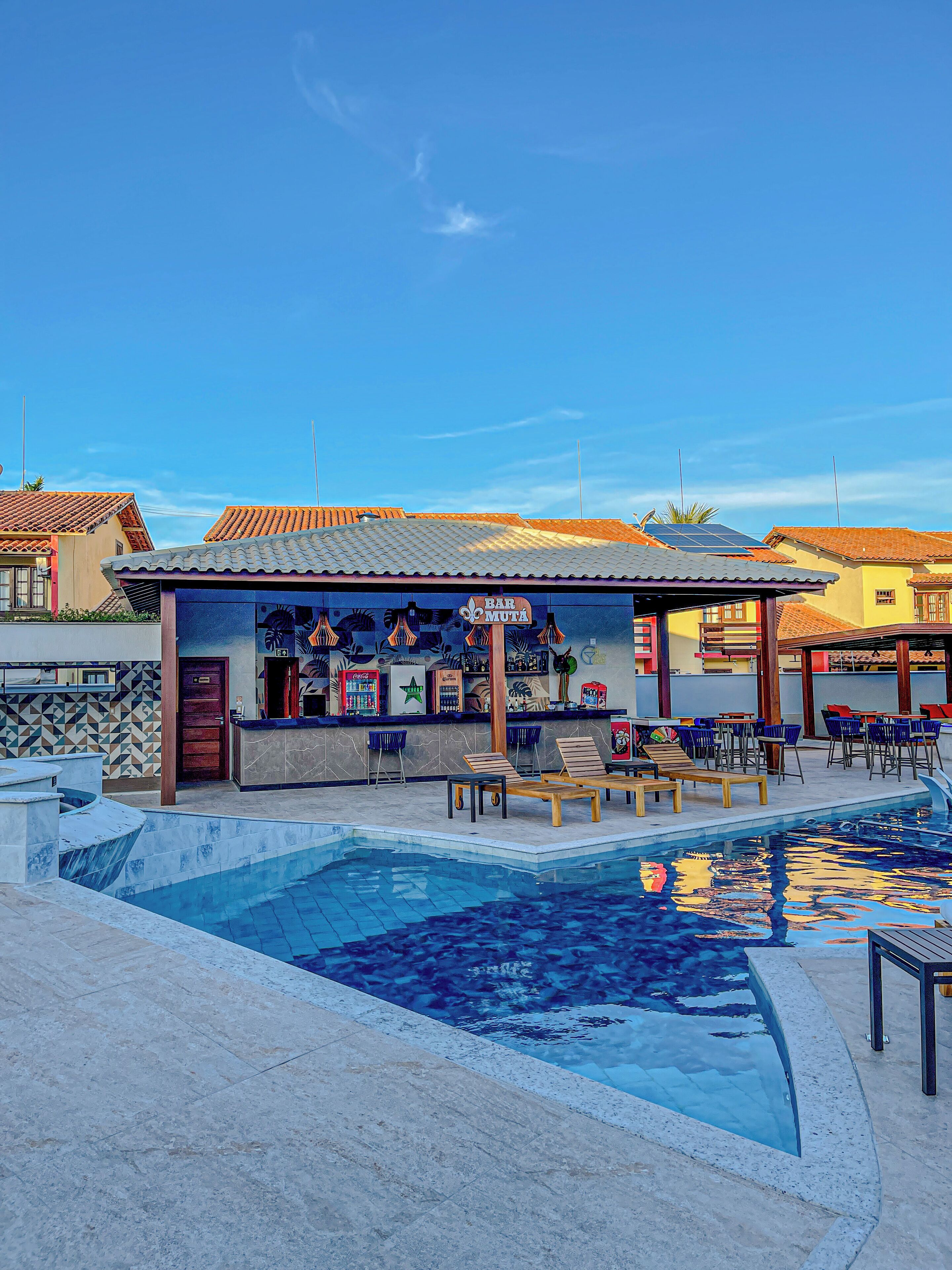 A bar with a tiled roof and a pool area with lounge chairs.