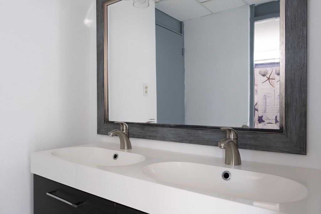 Un baño con dos lavamanos, un espejo grande y un mueble de color oscuro.