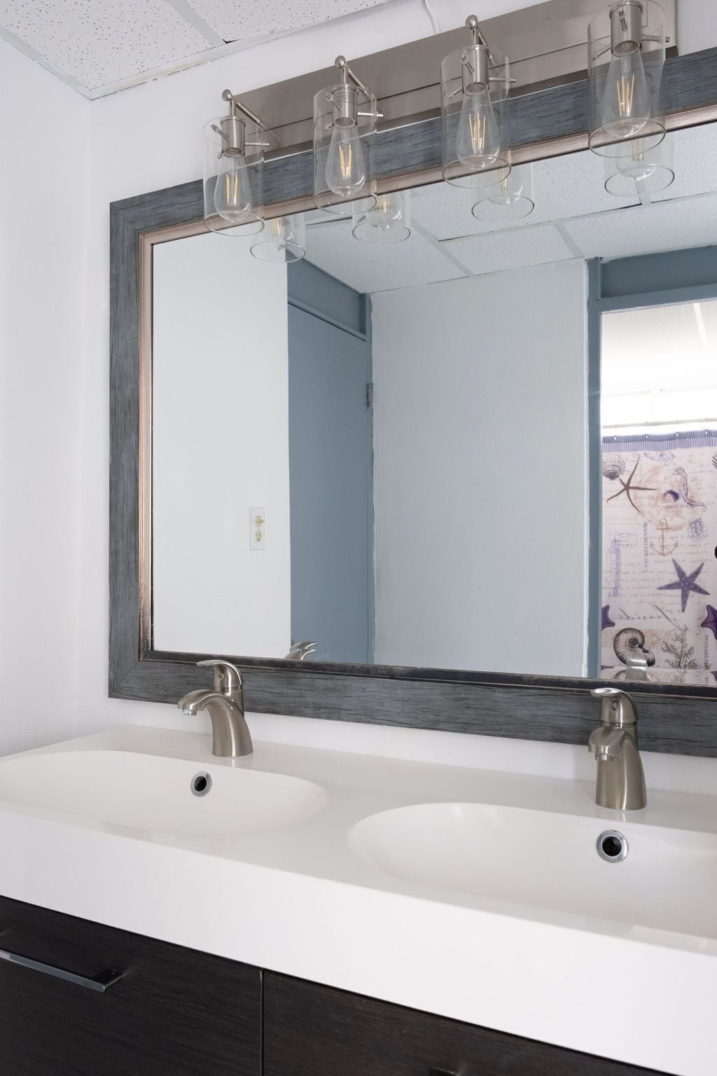 A bathroom with two sinks, a large mirror, and a light fixture above the mirror.