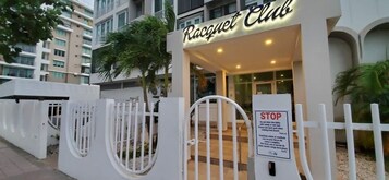 Entrada de un edificio con un letrero que dice 'Racquet Club' y una reja blanca con una señal de stop.
