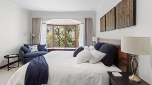 A hotel room with a large bed, a sofa, a small table, and a lamp. - Sublime Mountains Escape: Luxury & Serenity (Leura)