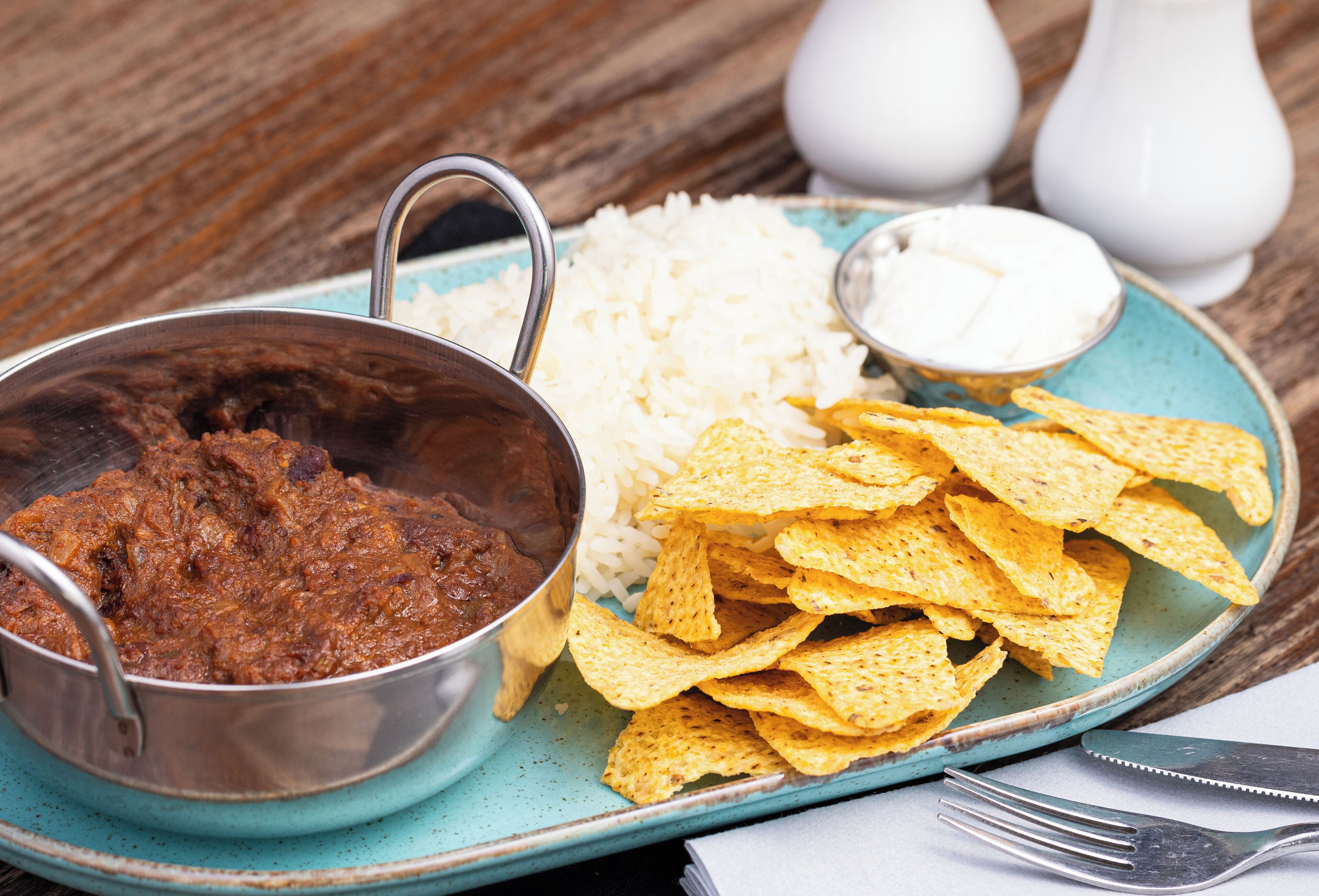 A plate with rice, tortilla chips, and a bowl of chili.