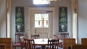 Uma sala de jantar com um candelabro, uma mesa redonda e seis cadeiras de madeira.
