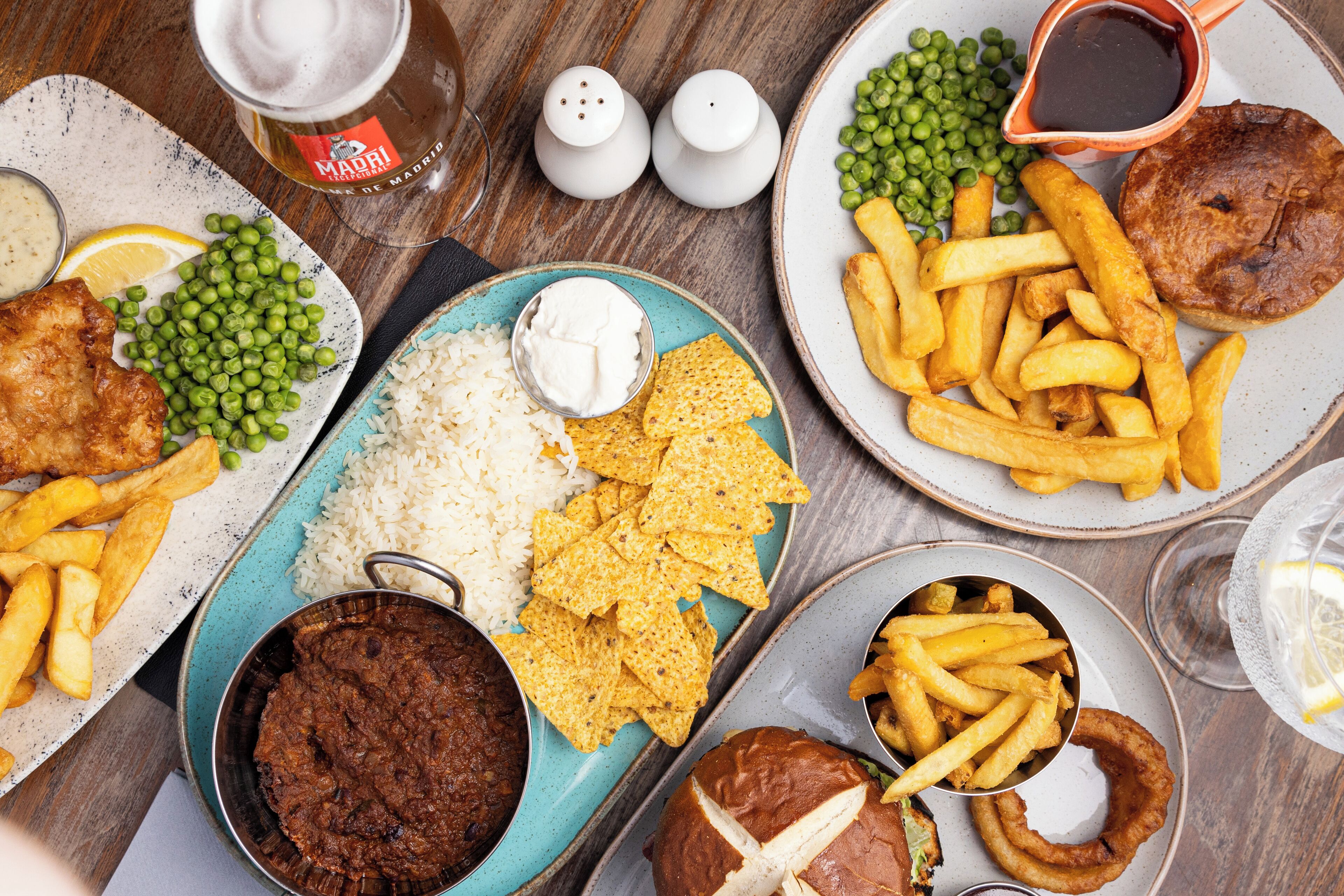 A table with various dishes including fish, peas, rice, chips, and a pie.