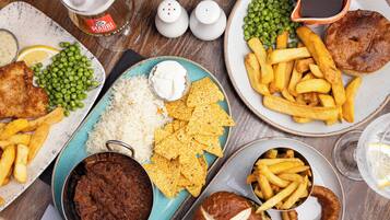 A table with various dishes including fish, peas, rice, chips, and a pie.