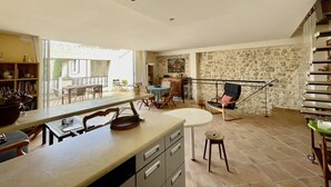 A spacious kitchen with a dining area, a staircase, and a view of the outdoors. - Village house “Stella” (Saint-Cannat)
