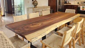 Una cocina moderna con armarios de madera oscura, un refrigerador de acero inoxidable y una amplia mesa de comedor de madera con sillas de mimbre.