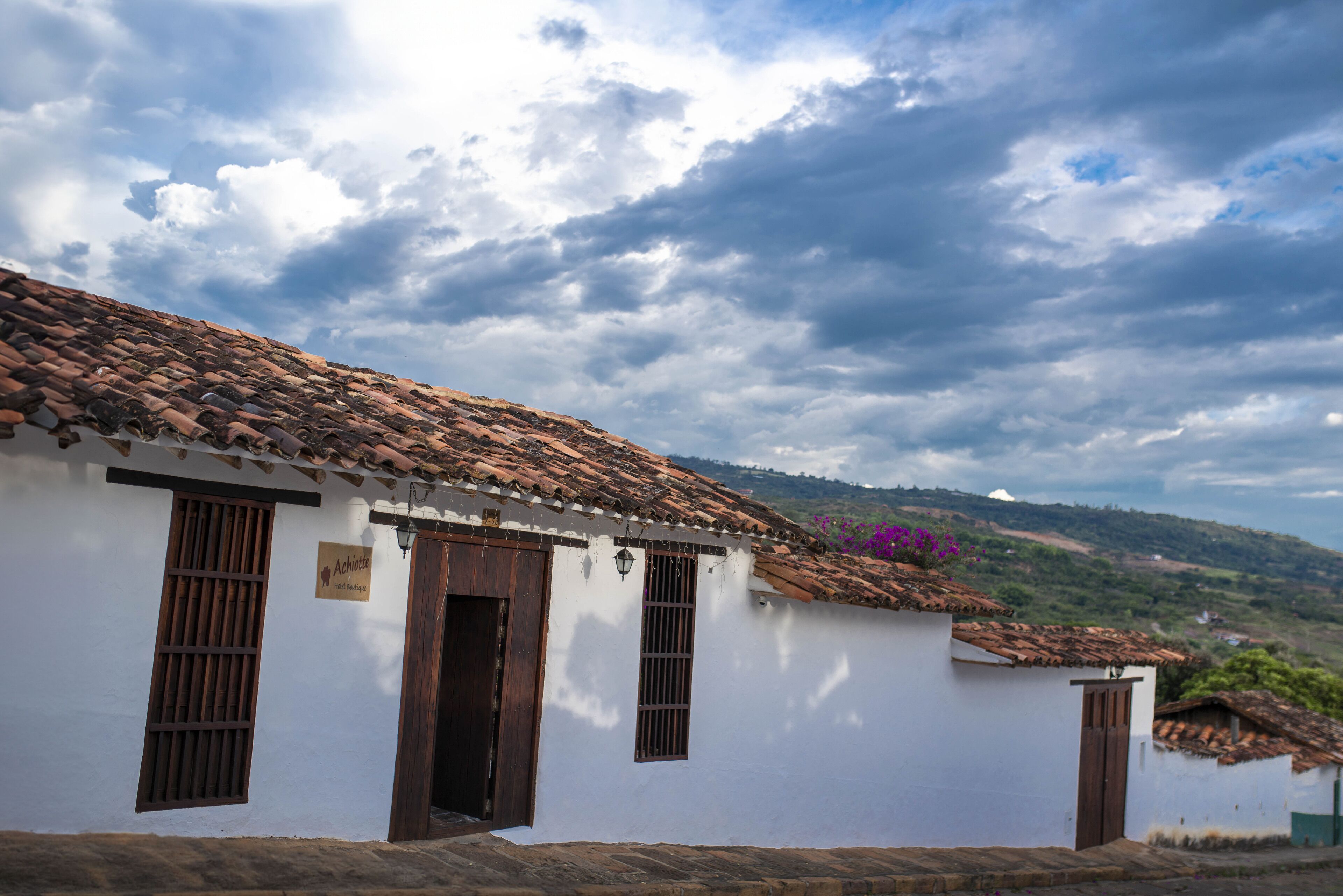 A traditional white building with a tiled roof, a wooden door, and a window with bars.