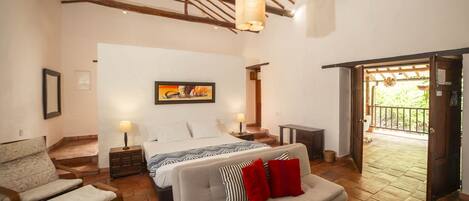 Une chambre à coucher comprenant un lit, un canapé, une chaise, un plafond en bois et une porte donnant sur un balcon.
