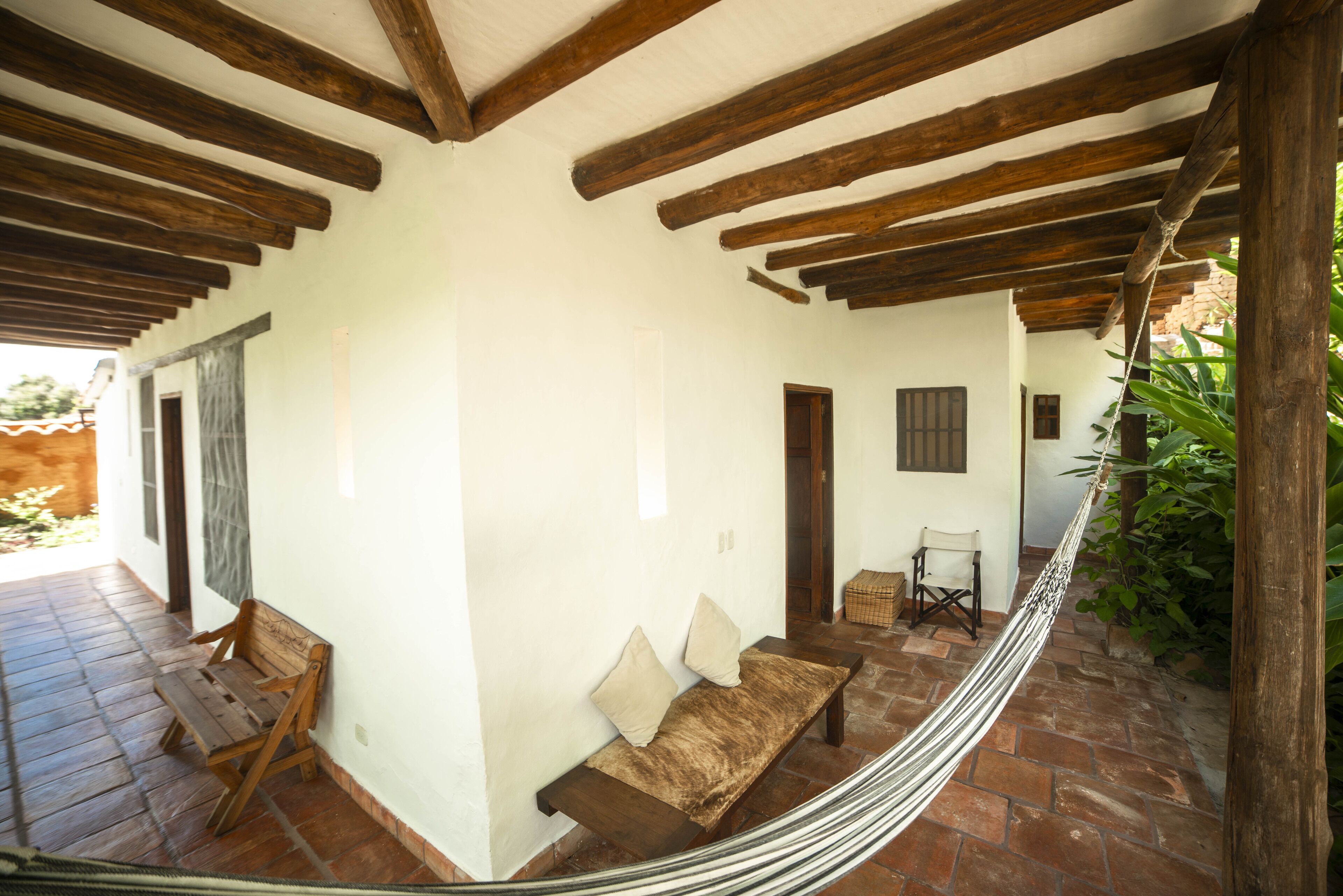 A covered outdoor area with a hammock, wooden benches, and a small table.
