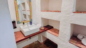 Un baño con un lavamanos blanco, un espejo con marco decorativo y una encimera de madera.