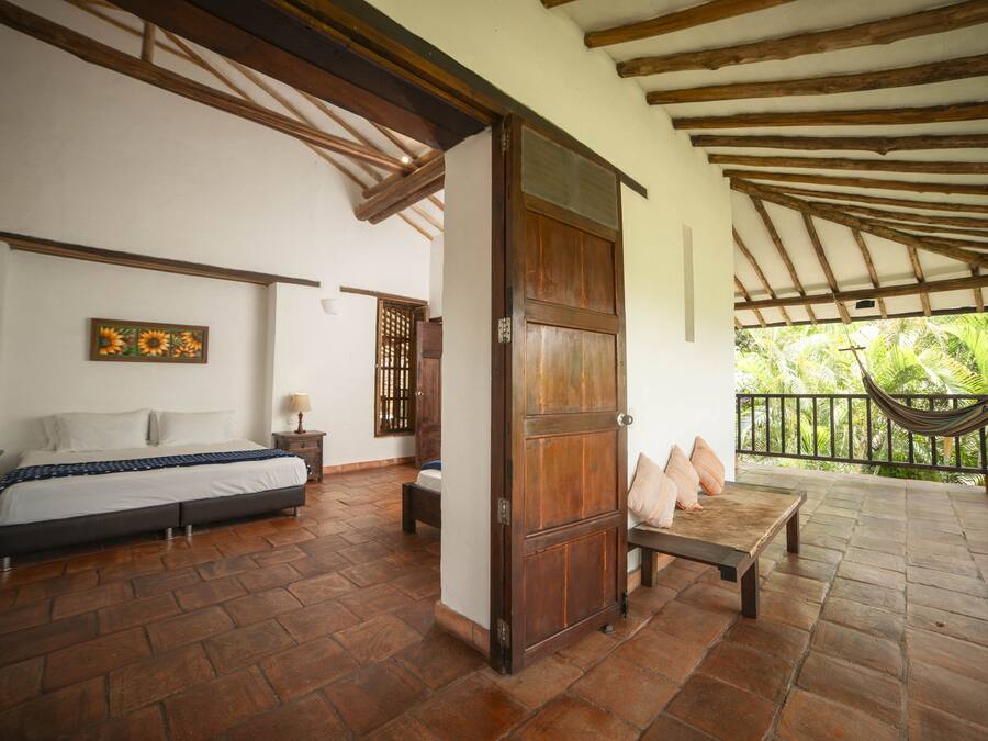 A bedroom with a bed, a wooden door, a bench, and a hammock.