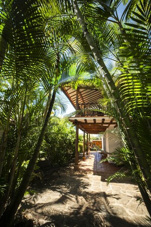A covered outdoor area with stone flooring, surrounded by dense green foliage. - Achiotte by Masaya Collection (Barichara)
