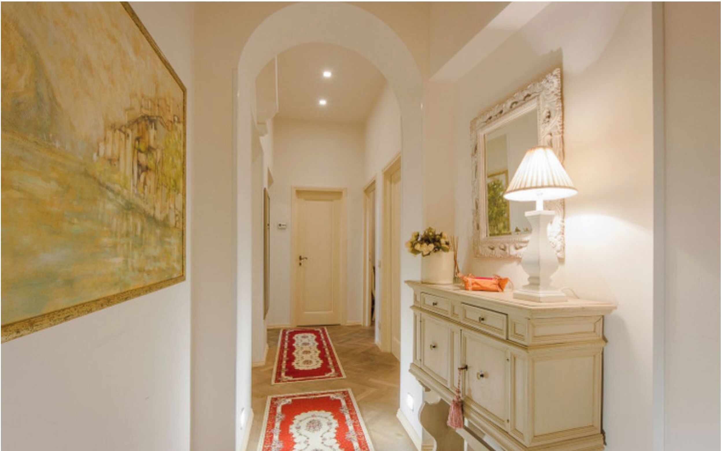 A hallway with a painting, a lamp, and a cabinet.