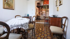 A dining area with a round table, chairs, a patterned floor, and a bookshelf in the background. - Apartments Florence- Sunny Via Romana (Firenze)