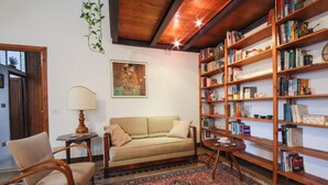 A cozy living room with a sofa, chairs, a bookshelf, and a patterned rug. - Apartments Florence- Sunny Via Romana (Firenze)
